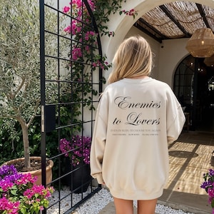 Minimalistisch “Enemies to Lovers” tekstdesign op hoodie, sweatshirt of T-shirt voor romance readers. Perfect voor fans van de enemies-to-lovers trope en bookish fashion. Zacht, comfortabel en ideaal om te dragen tijdens het lezen. Stijlvol cadeau voor boekenliefhebbers.