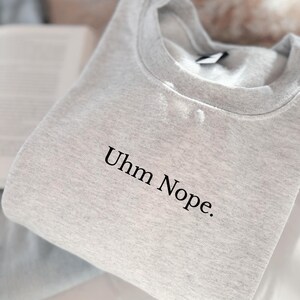 Geborduurd sweatshirt met de tekst “Uhm Nope.” in een minimalistisch lettertype. De trui heeft een comfortabele pasvorm en een rustige, stijlvolle uitstraling. Het ontwerp straalt humor, zelfbeschikking en duidelijke grenzen uit. Geschikt voor casual outfits, relaxmomenten of als origineel cadeau voor iemand die vandaag gewoon even nee zegt.