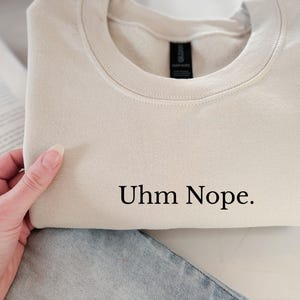 Geborduurd sweatshirt met de tekst “Uhm Nope.” in een minimalistisch lettertype. De trui heeft een comfortabele pasvorm en een rustige, stijlvolle uitstraling. Het ontwerp straalt humor, zelfbeschikking en duidelijke grenzen uit. Geschikt voor casual outfits, relaxmomenten of als origineel cadeau voor iemand die vandaag gewoon even nee zegt.