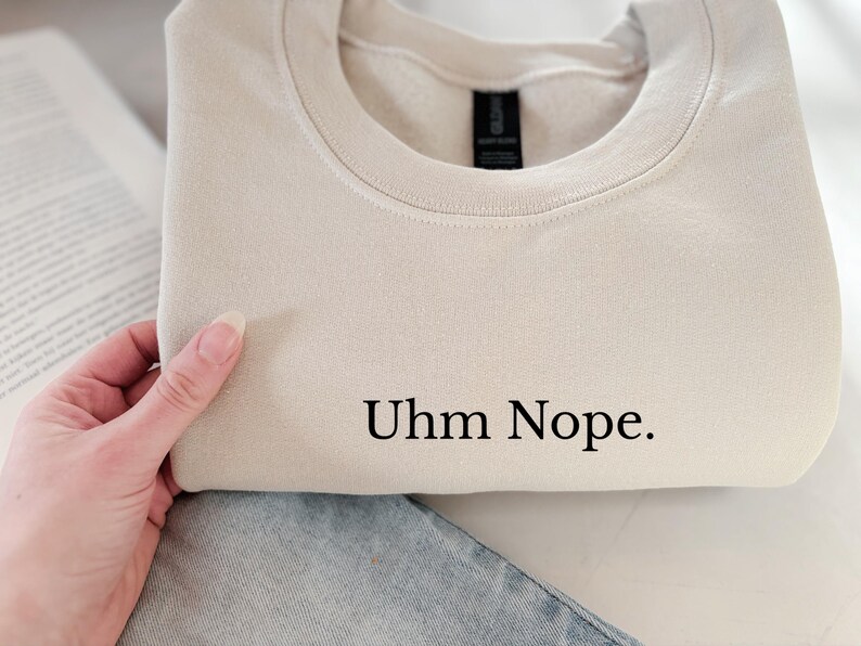 Geborduurd sweatshirt met de tekst “Uhm Nope.” in een minimalistisch lettertype. De trui heeft een comfortabele pasvorm en een rustige, stijlvolle uitstraling. Het ontwerp straalt humor, zelfbeschikking en duidelijke grenzen uit. Geschikt voor casual outfits, relaxmomenten of als origineel cadeau voor iemand die vandaag gewoon even nee zegt.