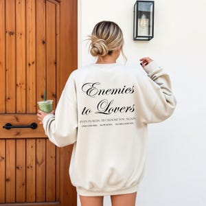 Minimalistisch “Enemies to Lovers” tekstdesign op hoodie, sweatshirt of T-shirt voor romance readers. Perfect voor fans van de enemies-to-lovers trope en bookish fashion. Zacht, comfortabel en ideaal om te dragen tijdens het lezen. Stijlvol cadeau voor boekenliefhebbers.