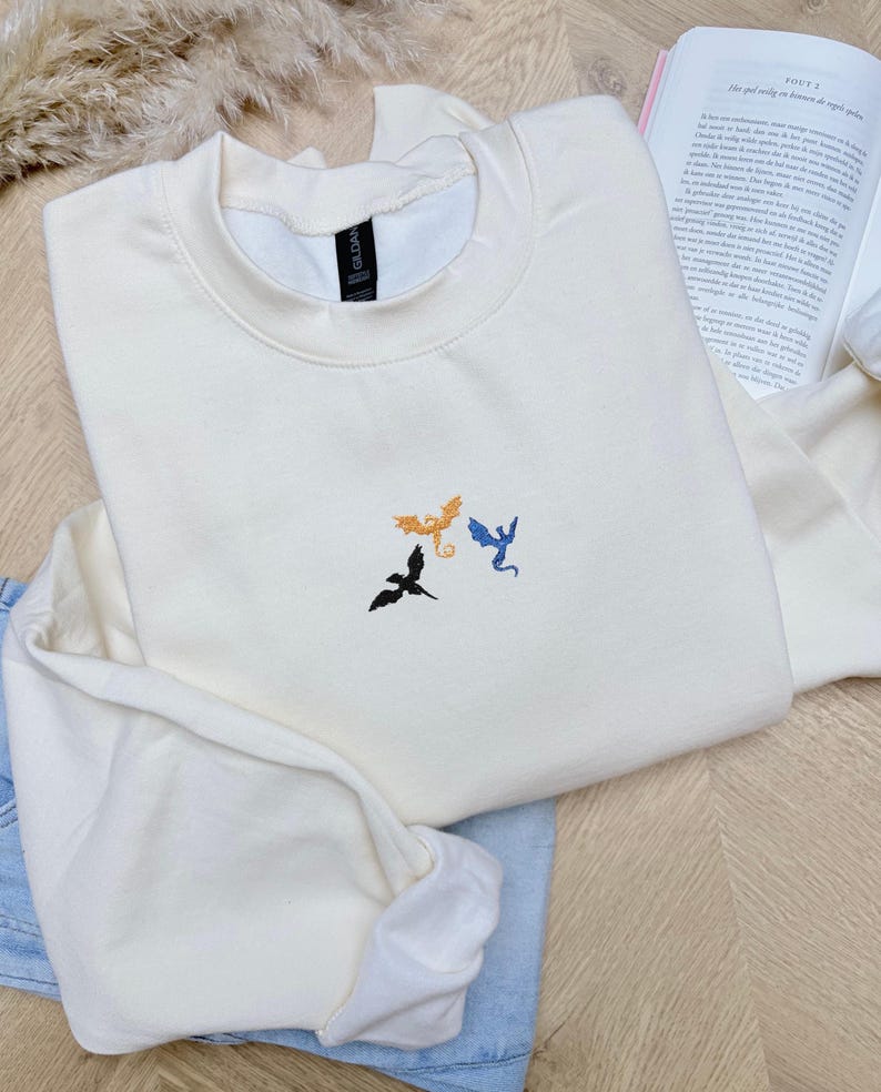 Embroidered dragon book sweatshirt for fantasy book lovers, cozy bookish dragon crewneck with detailed dragon embroidery. Perfect gift for readers, BookTok fans, librarians and fantasy readers. Aesthetic book lover sweatshirt inspired by dragons and magical stories, ideal bookish merch for reading lovers, dragon readers and fantasy literature fans.