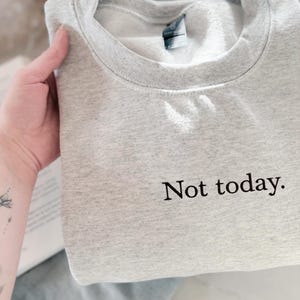 Grappige statement T-shirt met de tekst “Not today” in een minimalistisch en modern lettertype. Het ontwerp straalt humor, zelfverzekerdheid en duidelijke grenzen uit. Geschikt als casual outfit of comfy sweatshirtlook. Perfect als cadeau voor je vriendin of voor jezelf, voor iedereen die met een knipoog nee durft te zeggen. Tijdloos, stijlvol en makkelijk te combineren.