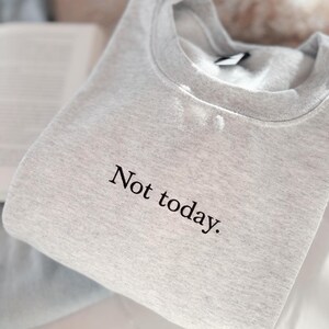 Grappige statement T-shirt met de tekst “Not today” in een minimalistisch en modern lettertype. Het ontwerp straalt humor, zelfverzekerdheid en duidelijke grenzen uit. Geschikt als casual outfit of comfy sweatshirtlook. Perfect als cadeau voor je vriendin of voor jezelf, voor iedereen die met een knipoog nee durft te zeggen. Tijdloos, stijlvol en makkelijk te combineren.