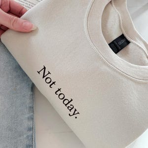 Grappige statement T-shirt met de tekst “Not today” in een minimalistisch en modern lettertype. Het ontwerp straalt humor, zelfverzekerdheid en duidelijke grenzen uit. Geschikt als casual outfit of comfy sweatshirtlook. Perfect als cadeau voor je vriendin of voor jezelf, voor iedereen die met een knipoog nee durft te zeggen. Tijdloos, stijlvol en makkelijk te combineren.