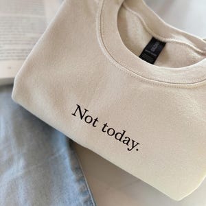 Grappige statement T-shirt met de tekst “Not today” in een minimalistisch en modern lettertype. Het ontwerp straalt humor, zelfverzekerdheid en duidelijke grenzen uit. Geschikt als casual outfit of comfy sweatshirtlook. Perfect als cadeau voor je vriendin of voor jezelf, voor iedereen die met een knipoog nee durft te zeggen. Tijdloos, stijlvol en makkelijk te combineren.
