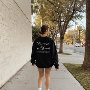 Minimalistisch “Enemies to Lovers” tekstdesign op hoodie, sweatshirt of T-shirt voor romance readers. Perfect voor fans van de enemies-to-lovers trope en bookish fashion. Zacht, comfortabel en ideaal om te dragen tijdens het lezen. Stijlvol cadeau voor boekenliefhebbers.