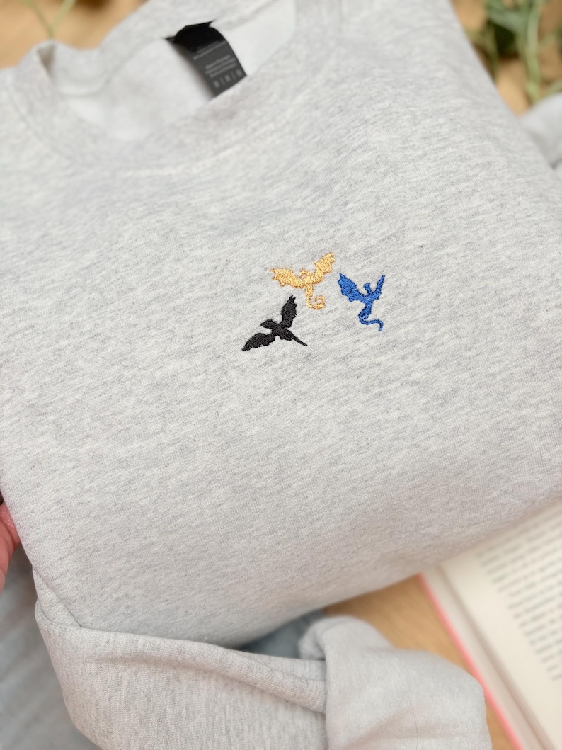 Embroidered dragon book sweatshirt for fantasy book lovers, cozy bookish dragon crewneck with detailed dragon embroidery. Perfect gift for readers, BookTok fans, librarians and fantasy readers. Aesthetic book lover sweatshirt inspired by dragons and magical stories, ideal bookish merch for reading lovers, dragon readers and fantasy literature fans.