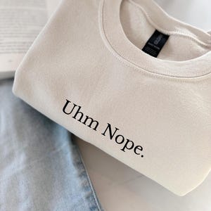 Geborduurd sweatshirt met de tekst “Uhm Nope.” in een minimalistisch lettertype. De trui heeft een comfortabele pasvorm en een rustige, stijlvolle uitstraling. Het ontwerp straalt humor, zelfbeschikking en duidelijke grenzen uit. Geschikt voor casual outfits, relaxmomenten of als origineel cadeau voor iemand die vandaag gewoon even nee zegt.