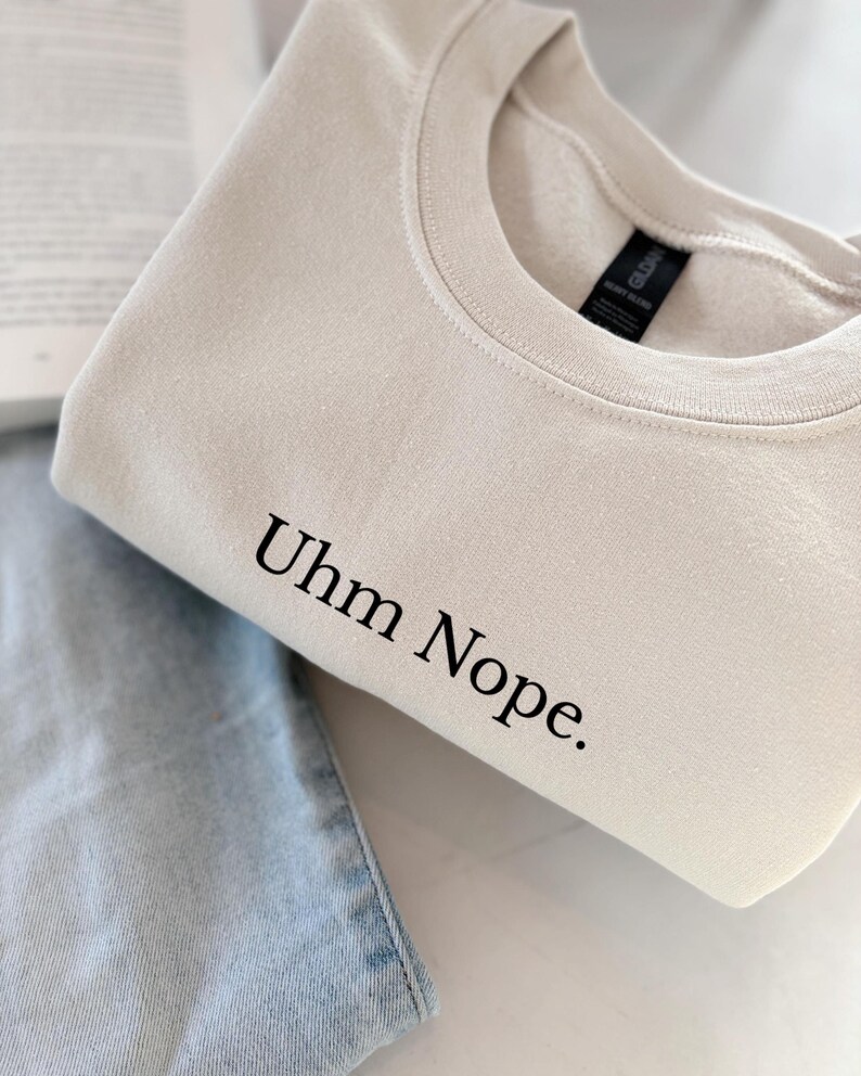 Geborduurd sweatshirt met de tekst “Uhm Nope.” in een minimalistisch lettertype. De trui heeft een comfortabele pasvorm en een rustige, stijlvolle uitstraling. Het ontwerp straalt humor, zelfbeschikking en duidelijke grenzen uit. Geschikt voor casual outfits, relaxmomenten of als origineel cadeau voor iemand die vandaag gewoon even nee zegt.