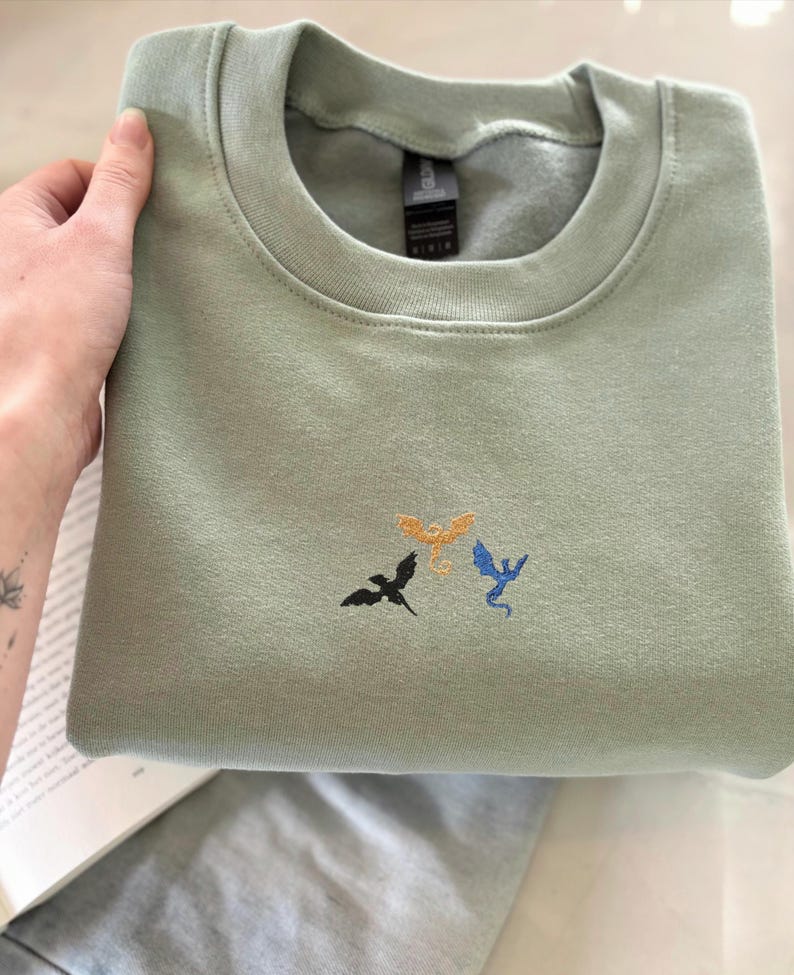 Embroidered dragon book sweatshirt for fantasy book lovers, cozy bookish dragon crewneck with detailed dragon embroidery. Perfect gift for readers, BookTok fans, librarians and fantasy readers. Aesthetic book lover sweatshirt inspired by dragons and magical stories, ideal bookish merch for reading lovers, dragon readers and fantasy literature fans.