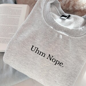 Geborduurd sweatshirt met de tekst “Uhm Nope.” in een minimalistisch lettertype. De trui heeft een comfortabele pasvorm en een rustige, stijlvolle uitstraling. Het ontwerp straalt humor, zelfbeschikking en duidelijke grenzen uit. Geschikt voor casual outfits, relaxmomenten of als origineel cadeau voor iemand die vandaag gewoon even nee zegt.