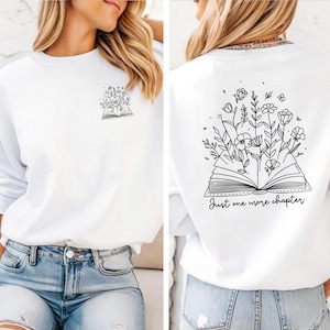 Een must-have voor elke boekenliefhebber! Deze comfy sweatshirt heeft een opvallend design met de tekst Just One More Chapter, een open boek en sierlijke bloemen. Dubbelzijdig bedrukt en verkrijgbaar in verschillende kleuren, maten én als T-shirt of hoodie. Perfect om in weg te kruipen met je favoriete verhaal – of dat ene hoofdstuk dat je móet uitlezen. Ideaal als cadeau of om je eigen leesverslaving te vieren! 📚✨