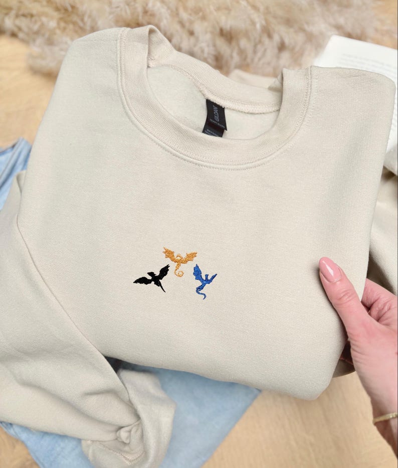 Embroidered dragon book sweatshirt for fantasy book lovers, cozy bookish dragon crewneck with detailed dragon embroidery. Perfect gift for readers, BookTok fans, librarians and fantasy readers. Aesthetic book lover sweatshirt inspired by dragons and magical stories, ideal bookish merch for reading lovers, dragon readers and fantasy literature fans.