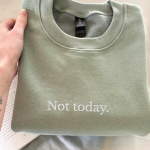 Grappige statement T-shirt met de tekst “Not today” in een minimalistisch en modern lettertype. Het ontwerp straalt humor, zelfverzekerdheid en duidelijke grenzen uit. Geschikt als casual outfit of comfy sweatshirtlook. Perfect als cadeau voor je vriendin of voor jezelf, voor iedereen die met een knipoog nee durft te zeggen. Tijdloos, stijlvol en makkelijk te combineren.