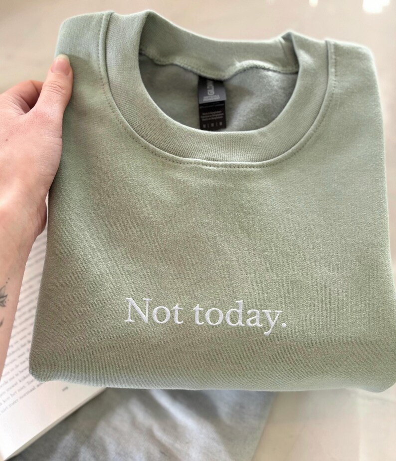 Grappige statement T-shirt met de tekst “Not today” in een minimalistisch en modern lettertype. Het ontwerp straalt humor, zelfverzekerdheid en duidelijke grenzen uit. Geschikt als casual outfit of comfy sweatshirtlook. Perfect als cadeau voor je vriendin of voor jezelf, voor iedereen die met een knipoog nee durft te zeggen. Tijdloos, stijlvol en makkelijk te combineren.