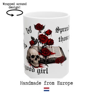 Op de afbeelding: Witte keramische mok met een gotisch ontwerp. Het heeft een schedel, rode rozen en een open boek. De mok heeft de zinnen "Spread those" en "good girl" erop gedrukt, samen met vlinderillustraties.