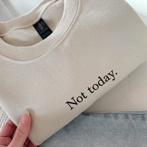 Grappige statement T-shirt met de tekst “Not today” in een minimalistisch en modern lettertype. Het ontwerp straalt humor, zelfverzekerdheid en duidelijke grenzen uit. Geschikt als casual outfit of comfy sweatshirtlook. Perfect als cadeau voor je vriendin of voor jezelf, voor iedereen die met een knipoog nee durft te zeggen. Tijdloos, stijlvol en makkelijk te combineren.