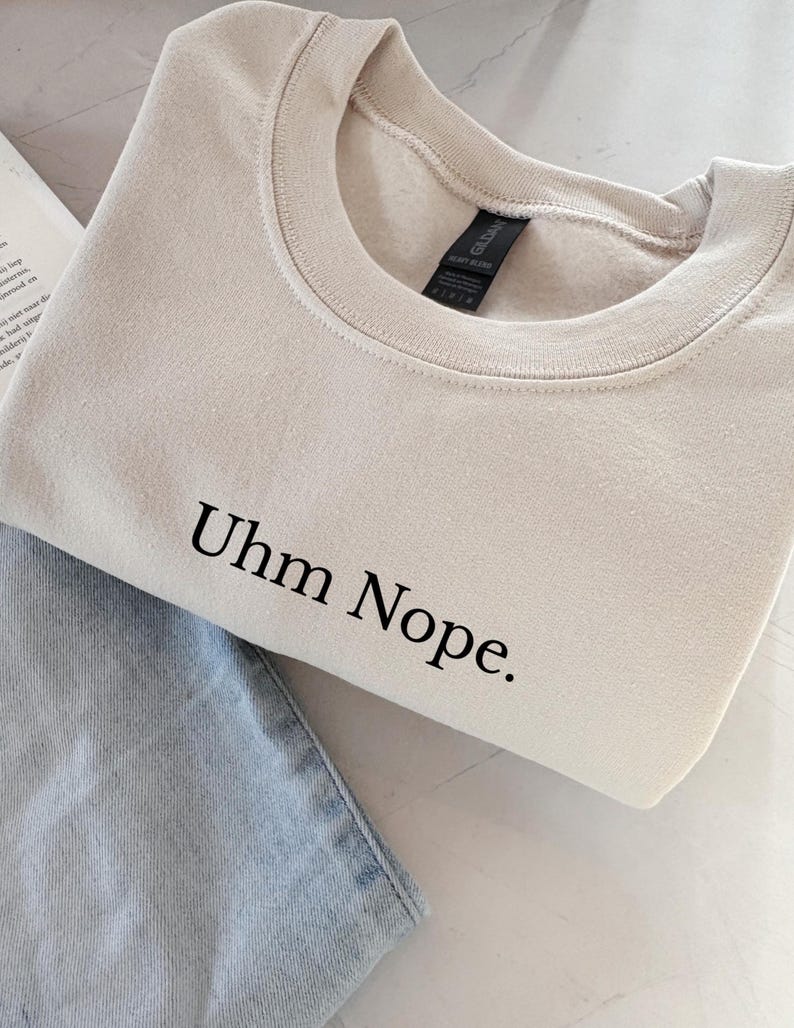 Geborduurd sweatshirt met de tekst “Uhm Nope.” in een minimalistisch lettertype. De trui heeft een comfortabele pasvorm en een rustige, stijlvolle uitstraling. Het ontwerp straalt humor, zelfbeschikking en duidelijke grenzen uit. Geschikt voor casual outfits, relaxmomenten of als origineel cadeau voor iemand die vandaag gewoon even nee zegt.
