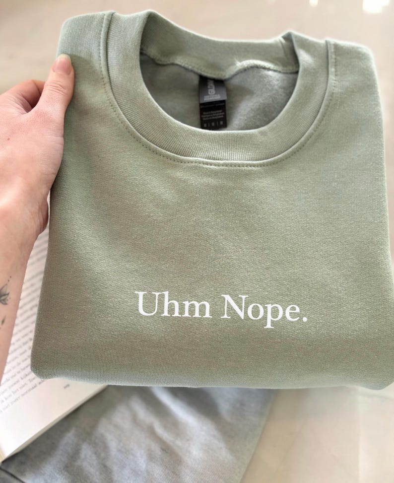 Geborduurd sweatshirt met de tekst “Uhm Nope.” in een minimalistisch lettertype. De trui heeft een comfortabele pasvorm en een rustige, stijlvolle uitstraling. Het ontwerp straalt humor, zelfbeschikking en duidelijke grenzen uit. Geschikt voor casual outfits, relaxmomenten of als origineel cadeau voor iemand die vandaag gewoon even nee zegt.