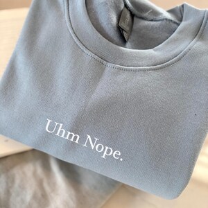 Geborduurd sweatshirt met de tekst “Uhm Nope.” in een minimalistisch lettertype. De trui heeft een comfortabele pasvorm en een rustige, stijlvolle uitstraling. Het ontwerp straalt humor, zelfbeschikking en duidelijke grenzen uit. Geschikt voor casual outfits, relaxmomenten of als origineel cadeau voor iemand die vandaag gewoon even nee zegt.