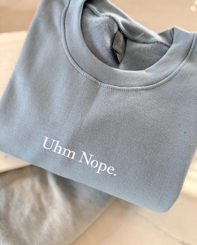 Geborduurd sweatshirt met de tekst “Uhm Nope.” in een minimalistisch lettertype. De trui heeft een comfortabele pasvorm en een rustige, stijlvolle uitstraling. Het ontwerp straalt humor, zelfbeschikking en duidelijke grenzen uit. Geschikt voor casual outfits, relaxmomenten of als origineel cadeau voor iemand die vandaag gewoon even nee zegt.