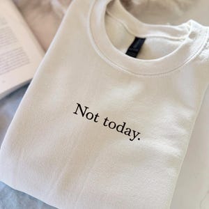 Grappige statement T-shirt met de tekst “Not today” in een minimalistisch en modern lettertype. Het ontwerp straalt humor, zelfverzekerdheid en duidelijke grenzen uit. Geschikt als casual outfit of comfy sweatshirtlook. Perfect als cadeau voor je vriendin of voor jezelf, voor iedereen die met een knipoog nee durft te zeggen. Tijdloos, stijlvol en makkelijk te combineren.