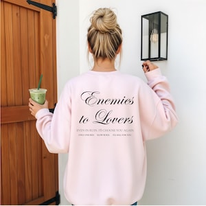 Minimalistisch “Enemies to Lovers” tekstdesign op hoodie, sweatshirt of T-shirt voor romance readers. Perfect voor fans van de enemies-to-lovers trope en bookish fashion. Zacht, comfortabel en ideaal om te dragen tijdens het lezen. Stijlvol cadeau voor boekenliefhebbers.