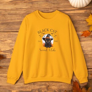 Schattige zwarte kat met een heksenhoed, perfect in Halloween-stijl, gedrukt op een comfortabel sweatshirt en t-shirt.