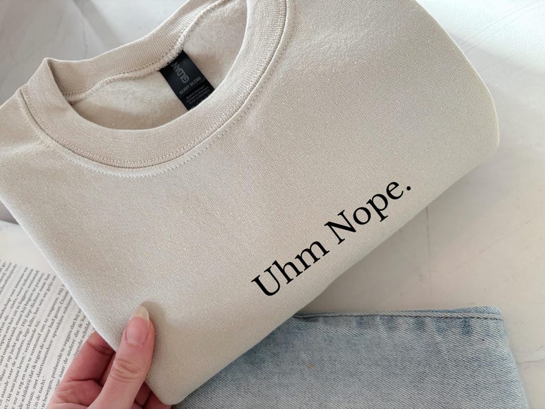 Geborduurd sweatshirt met de tekst “Uhm Nope.” in een minimalistisch lettertype. De trui heeft een comfortabele pasvorm en een rustige, stijlvolle uitstraling. Het ontwerp straalt humor, zelfbeschikking en duidelijke grenzen uit. Geschikt voor casual outfits, relaxmomenten of als origineel cadeau voor iemand die vandaag gewoon even nee zegt.