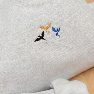 Embroidered dragon book sweatshirt for fantasy book lovers, cozy bookish dragon crewneck with detailed dragon embroidery. Perfect gift for readers, BookTok fans, librarians and fantasy readers. Aesthetic book lover sweatshirt inspired by dragons and magical stories, ideal bookish merch for reading lovers, dragon readers and fantasy literature fans.
