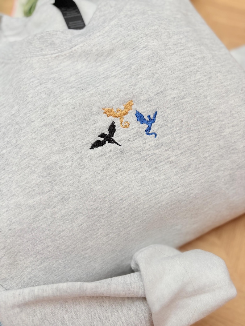 Embroidered dragon book sweatshirt for fantasy book lovers, cozy bookish dragon crewneck with detailed dragon embroidery. Perfect gift for readers, BookTok fans, librarians and fantasy readers. Aesthetic book lover sweatshirt inspired by dragons and magical stories, ideal bookish merch for reading lovers, dragon readers and fantasy literature fans.