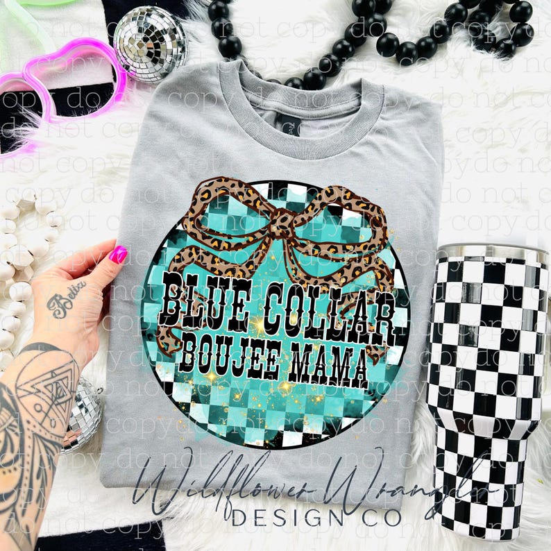May include: A light gray t-shirt with a circular graphic that reads "BLUE COLLAR BOUJEE MAMA". The graphic features a turquoise and black checkered background with a leopard print bow. A black and white checkered tumbler is also visible.