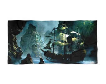 Può includere: Un telo mare rettangolare con un'illustrazione drammatica di una nave pirata spettrale che naviga attraverso un'insenatura rocciosa e nebbiosa. Le vele della nave sono a brandelli e la scena è resa in tonalità di blu, verde e nero.