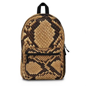 May include: A backpack featuring a snakeskin design in brown and tan hues. It has a black top handle, a front zipped pocket, and a black zip. The pattern is designed to resemble reptile skin.
