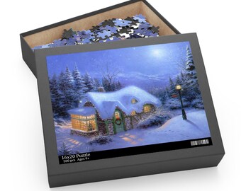 May include: A 16x20 inch puzzle box with a winter scene of a snow-covered cottage, lit windows, and a Christmas wreath. The box is open, revealing puzzle pieces. Text on the box reads "16x20 Puzzle 500 pcs Ages 9+".