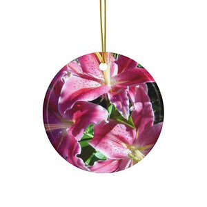 May include: Close-up of pink lilies with white speckles. The lilies are in focus and the background is blurred.