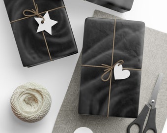 May include: Overhead shot of three black wrapped gifts tied with twine and white tags. One tag is a star, another a heart. A ball of twine, scissors, and additional blank tags are also present.