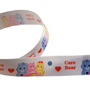 K&ouml;nnte beinhalten: Wei&szlig;es Band mit Care Bears-Figuren, Herzen und Punkten. Das Band zeigt die Worte "Care Bear" in Rot. Das Band ist gewellt und eignet sich f&uuml;r Bastelarbeiten oder zum Verpacken von Geschenken.