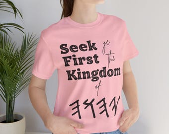 May include: Pink t-shirt with the text "Seek ye first the Kingdom of" and a symbol below.