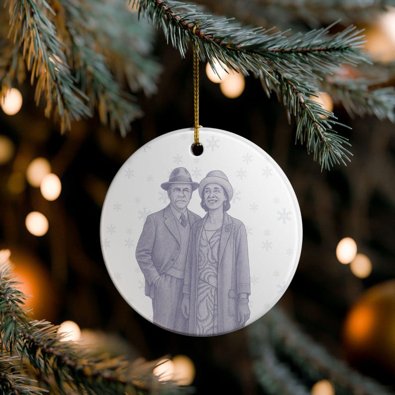 May include: A round, white Christmas ornament with a gold string, featuring a vintage illustration of a couple in hats and coats. The image is in shades of purple, with snowflake accents. The ornament hangs from a green Christmas tree branch.
