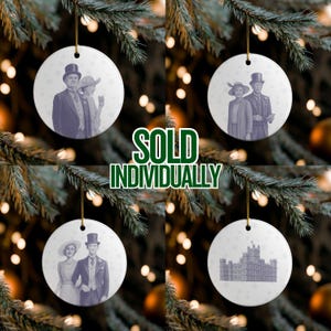 May include: Four white ceramic Christmas ornaments with gold string hangers. Each ornament features a vintage illustration of a couple or a building. The text "SOLD INDIVIDUALLY" is in green.