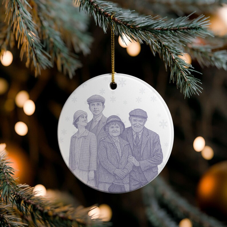 May include: A round, white Christmas ornament with a family portrait in a vintage style. The illustration is in shades of purple and features five people. The ornament is hanging from a gold string, with snowflakes in the background.