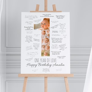 Może przedstawiać: Biały znak na drewnianym sztaludze z napisem "ONE YEAR OF LOVE Happy Birthday Amalia". Znak zawiera kolaż zdjęć dziecka i odręczne wiadomości. Znak jest przeznaczony na uroczystość urodzinową.