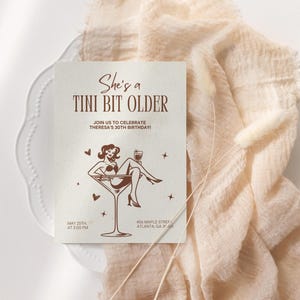 May include: A brown invitation card with the text "She's a Tini Bit Older" and a graphic of a woman sitting in a martini glass. The text "Join us to celebrate Theresa's 30th Birthday!" is also included. The date and time of the event are listed as "May 25th at 2:00 PM".