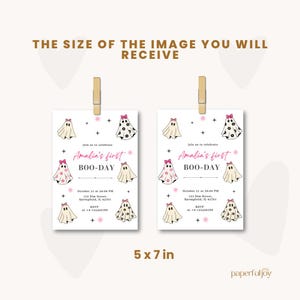 May include: Two Halloween-themed invitations, each 5 x 7 inches, are displayed. The invitations feature ghost illustrations with pink bows and the text "Amalia's first BOO-DAY". The invitations are held by wooden clips.