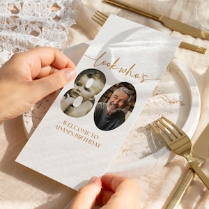 Könnte beinhalten: Eine rechteckige weiße Papierkarte mit dem Text "look who's" in goldener Schreibschrift und "WELCOME TO ADAM'S BIRTHDAY" in goldenen Blockbuchstaben. Zwei ovale Fotorahmen zeigen ein Kind und einen Erwachsenen zur Feier des 80. Geburtstags.