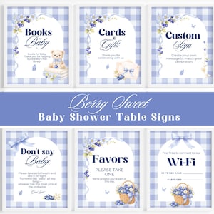 May include: A set of six framed baby shower table signs with a blue and white gingham background. The signs include text such as "Books for Baby", "Cards & Gifts", and "Wi-Fi". Each sign features watercolor illustrations of blueberries and teddy bears.
