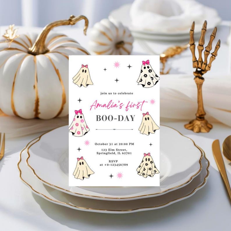 May include: A Halloween-themed invitation with the text "Amalia's first BOO-DAY" and ghost illustrations. The invitation is on a white plate with gold trim, with white pumpkins and a gold skeleton hand in the background.