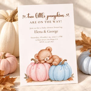 May include: A white baby shower invitation card featuring the brown text two little pumpkins ARE ON THE WAY! Join us for a baby shower honoring Elena & George. A watercolor illustration of a brown teddy bear sleeping on a pink and blue pumpkin.